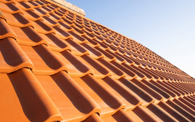 Overlapping rows of yellow ceramic roofing tiles covering reside Overlapping rows of yellow ceramic roofing tiles covering residential building roof.